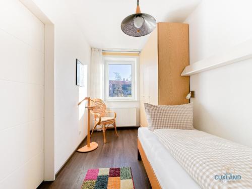 una piccola camera da letto con un letto e una sedia di Ferienwohnung 19 Heinrich-Grube Weg a Döse