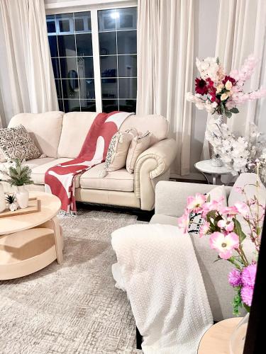 a living room with white furniture and pink flowers at Spacious & Comfy Upper Floor 3BR Suite in Detached House in Calgary