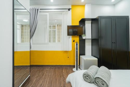 a room with a bed and a tv and a yellow wall at Elva Shine Dalat Hotel in Da Lat