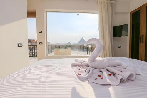 een witte handdoekzwaan die op een bed zit bij Pyramids View Hotel in Caïro