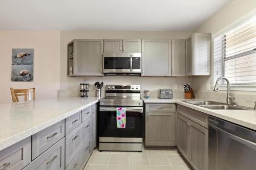a kitchen with stainless steel appliances and white cabinets at Waikoloa retreat with BBQ & pool access in Waikoloa Village