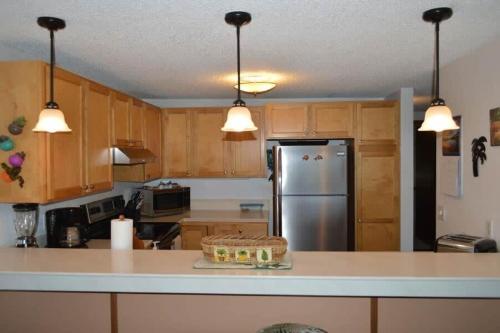 a kitchen with wooden cabinets and a stainless steel refrigerator at Peaceful golf retreat with shared pools in Waikoloa Village