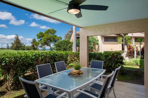 a patio with a table and chairs and a ceiling fan at Tropical condo with pools lanai & BBQ in Waikoloa Village