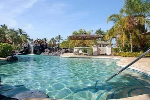 a swimming pool with blue water in a resort at Spacious retreat with pool & private lanai in Waikoloa