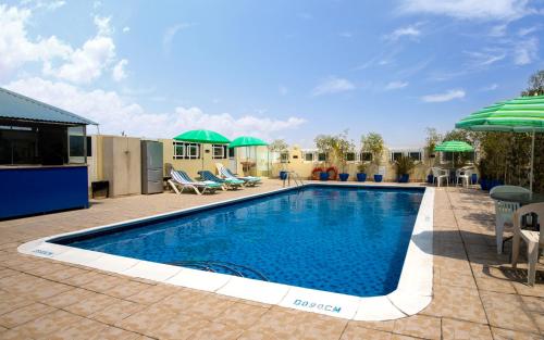 einen Pool mit Stühlen und Sonnenschirmen auf einer Terrasse in der Unterkunft Benta Grand Hotel LLC in Dubai