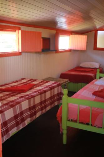 two beds in a room with red and green at Casa Galeguita in Pipa