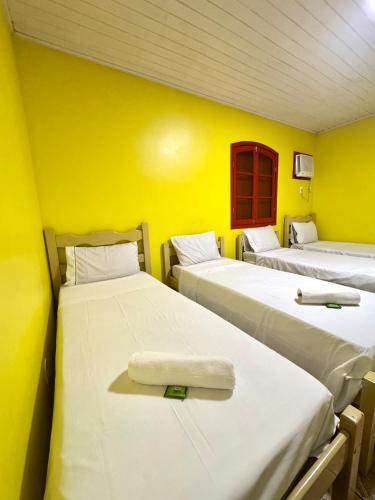 a room with three beds with yellow walls at Sea Blue Suites in Angra dos Reis
