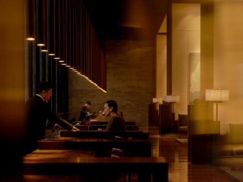 two people sitting at a bar in a restaurant at The PuLi Shanghai in Shanghai