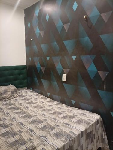 a bedroom with a bed with a geometric wall at Flat aconchegante na maraponga in Fortaleza