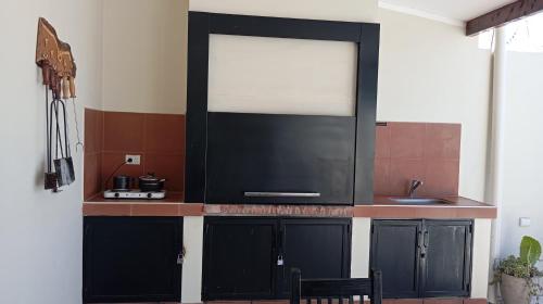 een keuken met zwarte kasten en een spoelbak bij Quincho Russo in Cerrillos