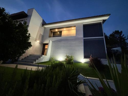 a large white house with lights on it at Colina de Picoutos Moradia com piscina in Póvoa de Lanhoso