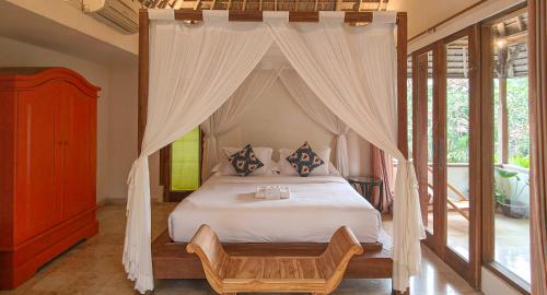 a bedroom with a canopy bed with a wooden frame at Shelter Island in Ubud