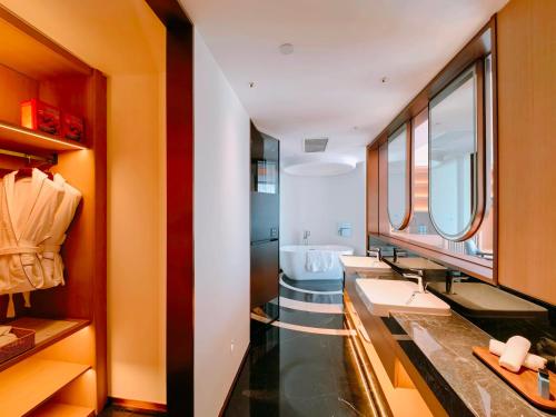 a bathroom with three sinks and a bath tub at The Purple Horse Hotel Beijing in Beijing