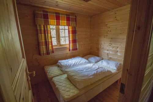 a small bed in a wooden room with a window at Strandbu in Viksdalen