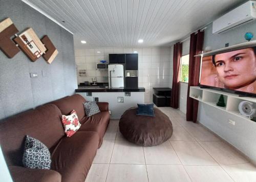 een woonkamer met een bank en een groot scherm bij Casa Aconchegante in Guarujá