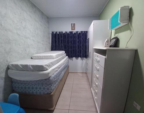 een slaapkamer met twee bedden en een commode met een blauw gordijn bij Casa Aconchegante in Guarujá
