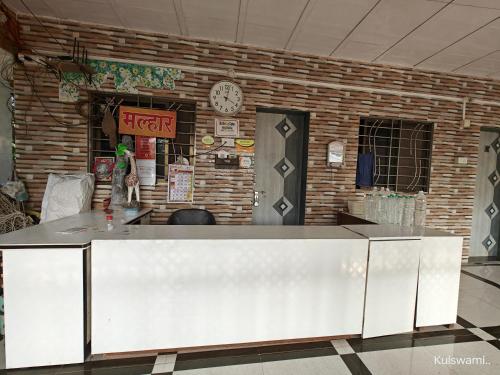 a counter in front of a brick wall with a clock at Kulswami Cottage Alibag in Alibaug