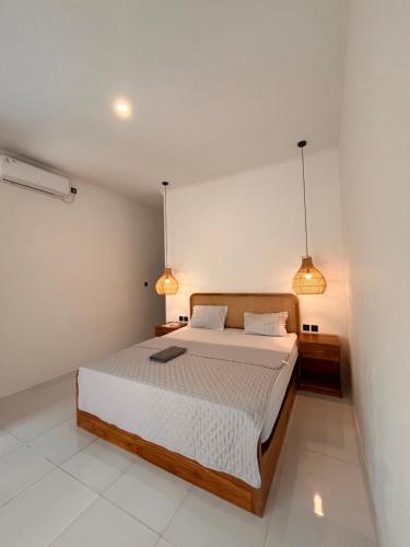 a bedroom with a large bed with two lights at PAN Homestay in Kuta Lombok