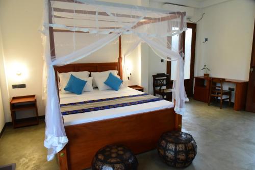 Un dormitorio con una cama con dosel y almohadas azules. en Moon Lanka Hotel Hikkaduwa, en Hikkaduwa