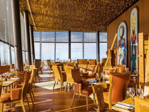 a restaurant with tables and chairs and windows at Too Hotel & Spa Paris - MGallery Collection in Paris