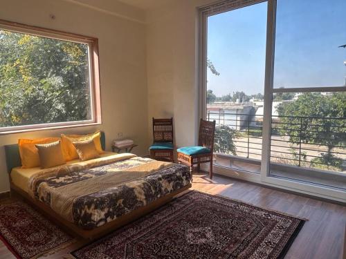 een slaapkamer met een bed en 2 grote ramen bij Mangal Uday Villa in Jaipur