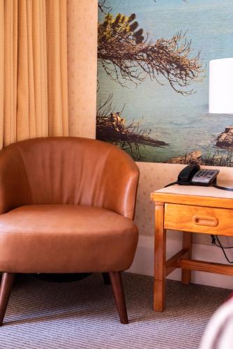a brown chair sitting next to a table with a telephone at European Hotel in Perth