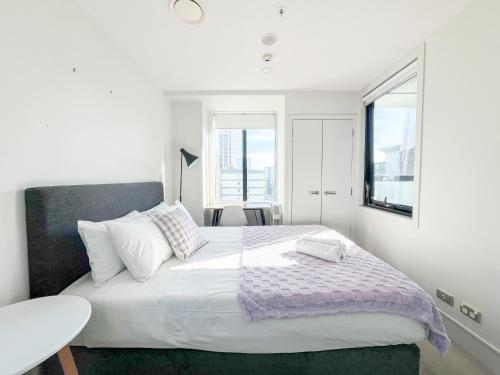 a white bedroom with a large bed and a window at Sky Tower Views 2BR Retreat Wit h FREE Pool Gym in Auckland