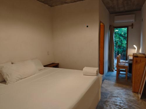 a bedroom with a bed and a chair and a window at Casa Momo Playa Zipolite Oaxaca in Zipolite