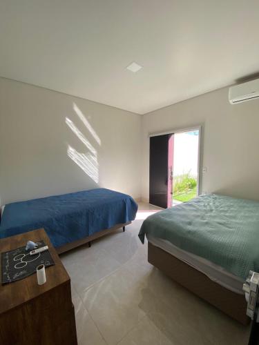 a bedroom with two beds and a table and a window at Casas Paradisiaca aleatória l , ll ou lll ou lV Pagamento Automática in Caldas Novas