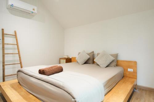 a bedroom with a white bed with a ladder at กู๊ดวิวแคมป์ชะอม in Ban Bung Mai