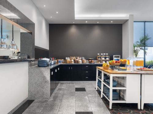 una cocina con armarios negros y una mesa con frutas. en Mantra Melbourne Airport, en Melbourne