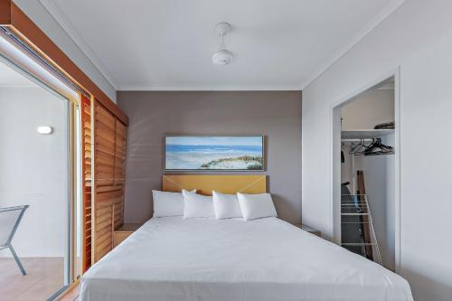 een slaapkamer met een groot wit bed en een raam bij Spa Haven 18B in Airlie Beach