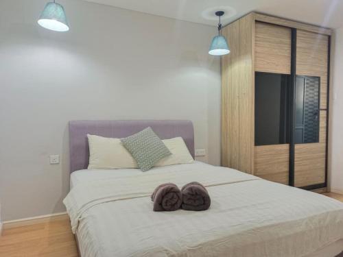 een slaapkamer met een bed met twee slippers erop bij Nordic Residences in Melaka