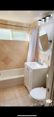 a bathroom with a toilet and a sink and a tub at Pretty bedroom with shared bathroom in Hacienda Heights