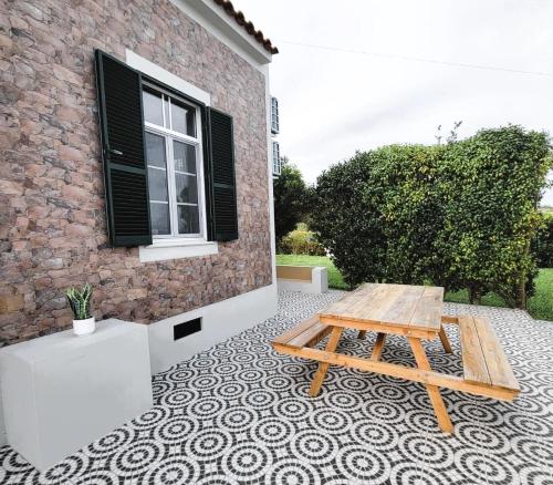Ein hölzerner Picknicktisch auf einem gefliesten Boden vor einem Gebäude in der Unterkunft Cozy Nest in Bretanha