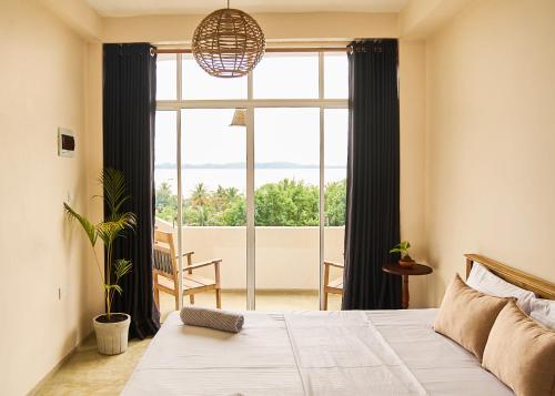 een slaapkamer met een bed en een groot raam bij Casa Banana in Weligama