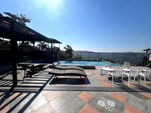 a swimming pool with tables and chairs on a patio at Vandhaara Luxury Stays in Pune