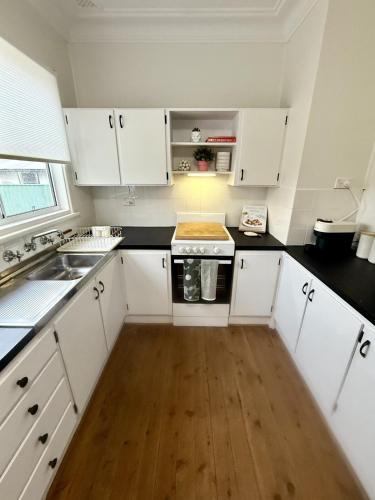 a kitchen with white cabinets and a wooden floor at Saltwater Escape in Swansea