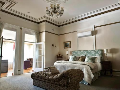 a bedroom with a bed and a chair and a chandelier at Claremont Oak Estate in Launceston
