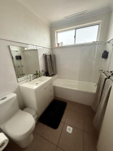 a white bathroom with a toilet and a tub and a sink at Saltwater Escape in Swansea