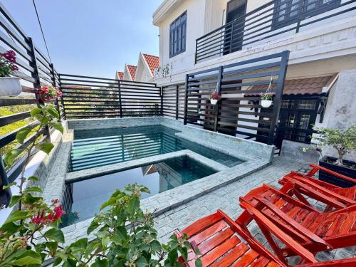 een zwembad naast twee stoelen en een gebouw bij SOMA Villa in Phumĭ Réach Born