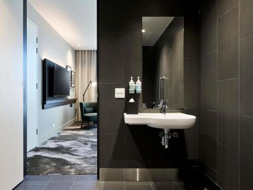 a bathroom with a sink and a tv in a room at Novotel Melbourne Airport in Melbourne