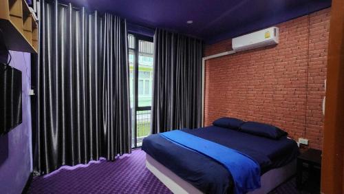 een slaapkamer met een bed en een bakstenen muur bij Ber Ben House in Bang Su