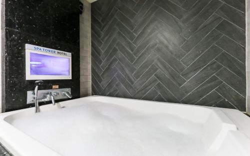 eine Badewanne im Bad mit einem TV in der Unterkunft Spa Tower Motel in Daejeon