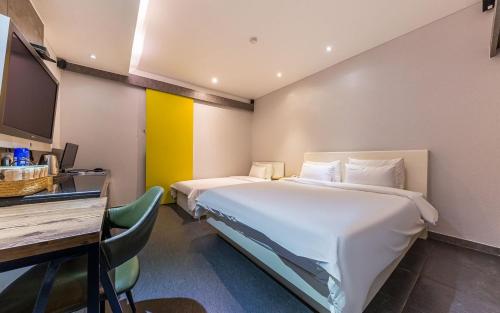 ein Hotelzimmer mit zwei Betten und einem Tisch und einem Schreibtisch in der Unterkunft Spa Tower Motel in Daejeon
