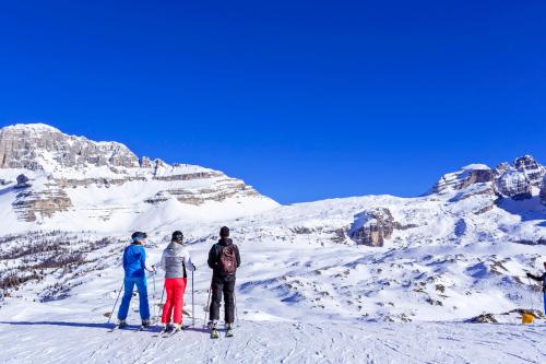 three people standing on top of a snow covered mountain at Hotel Chalet Del Sogno in Madonna di Campiglio