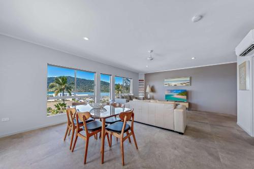 een eetkamer met een tafel en stoelen en een keuken bij Spa Haven 18A in Airlie Beach