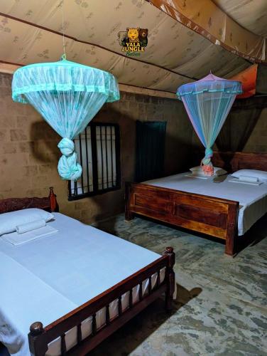 two beds in a room with blue curtains at Yala Jungle Haven in Yala