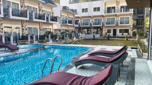 een zwembad met stoelen naast een gebouw bij Amritara Chakra River Resort in Mohan Chatti