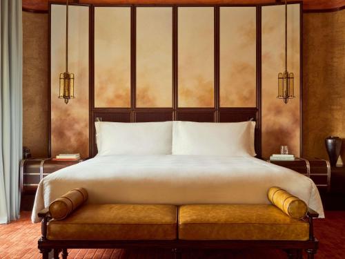 Un dormitorio con una cama grande con un banco en ella. en Orient Express La Minerva, en Roma